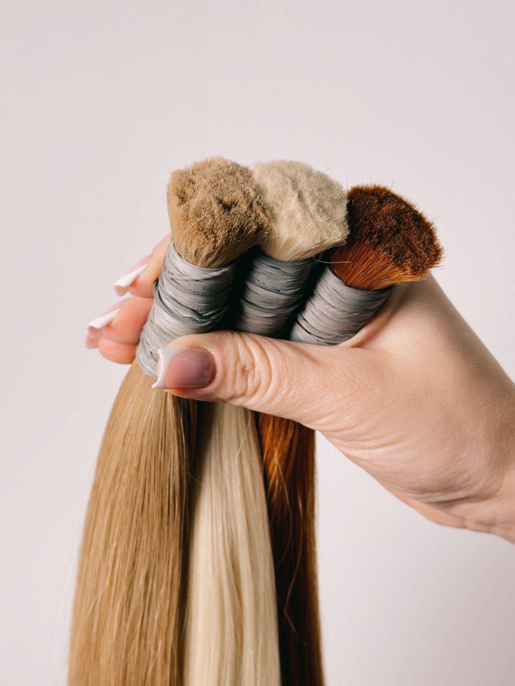 Мастер AllHairs держит пряди для наращивания в трёх оттенках